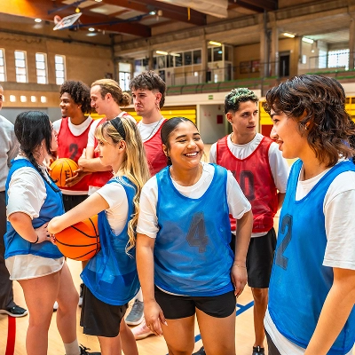 two teams of teens wearing red and blue jerseys smiling and shaking hands